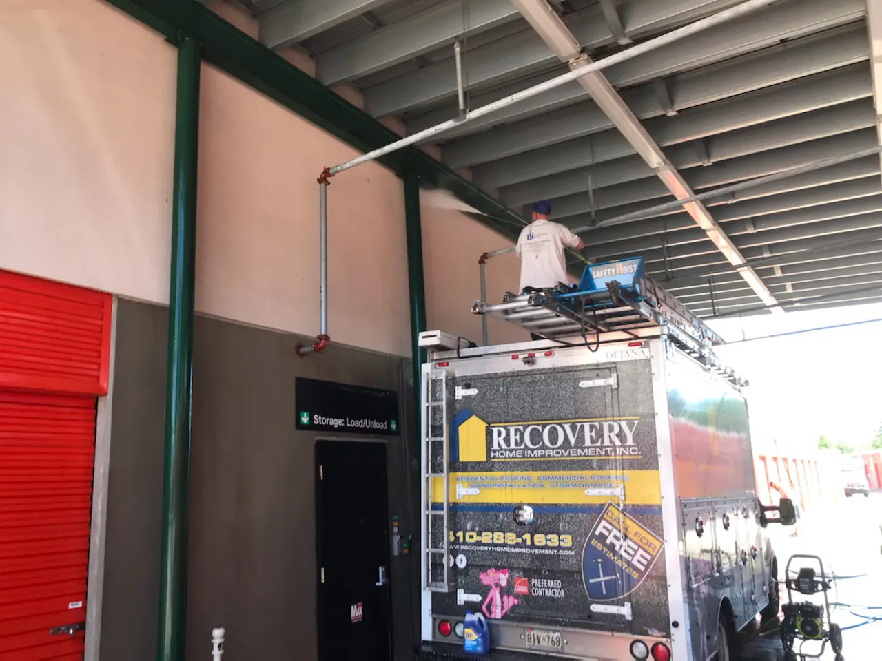 A man is working on sitting on the top of the van